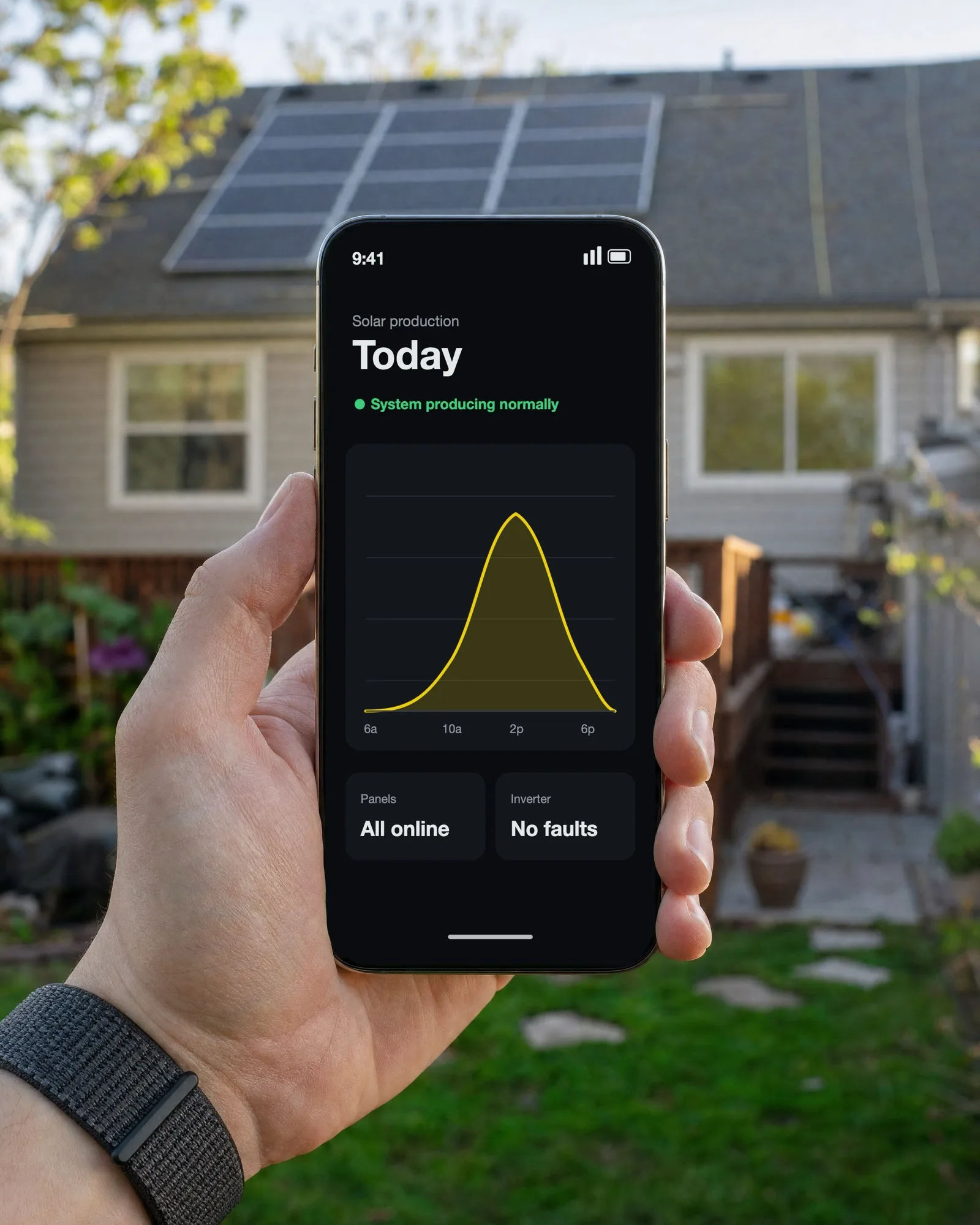 Phone showing a solar production app in front of a home with rooftop solar